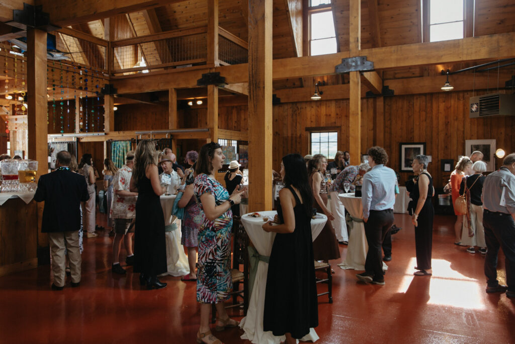 Groups of people stand talking inside the Larson Barn in Steamboat.