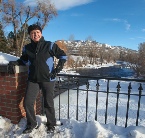 Catherine Carson poses on a bridge over the Yampa River, snow in the background.