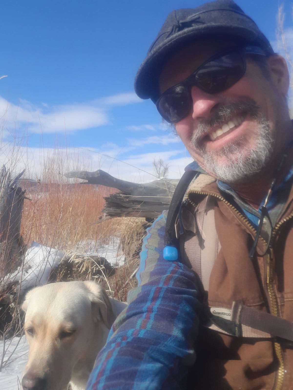 Headshot of Si Axtell and his yellow lab with bushes in the background.