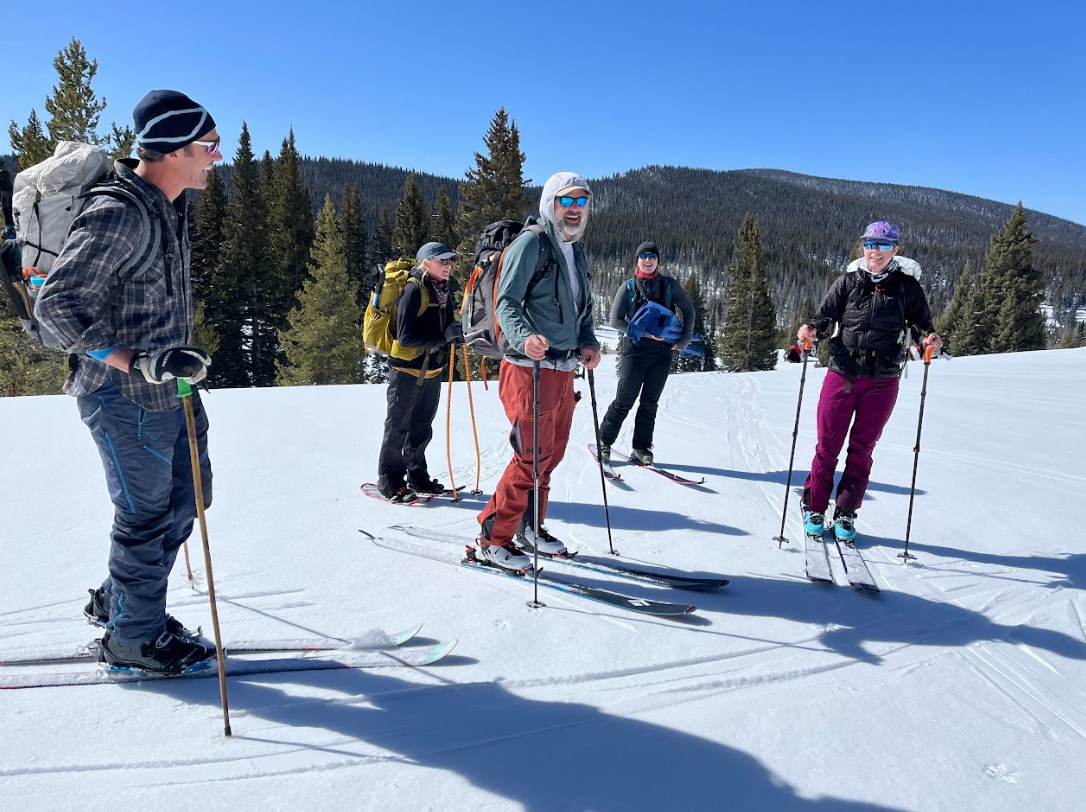 A group of five people stand on backcountry skis on top of the snow near Rabbit Ears Pass.