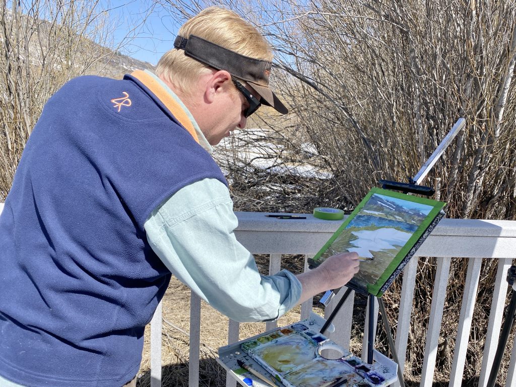 A painter painting cottonwoods and the riverbank.